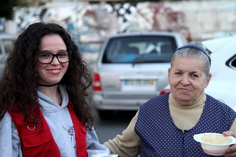 Voluntária do programa Anjos da Noite a entregar uma refeição a uma senhora